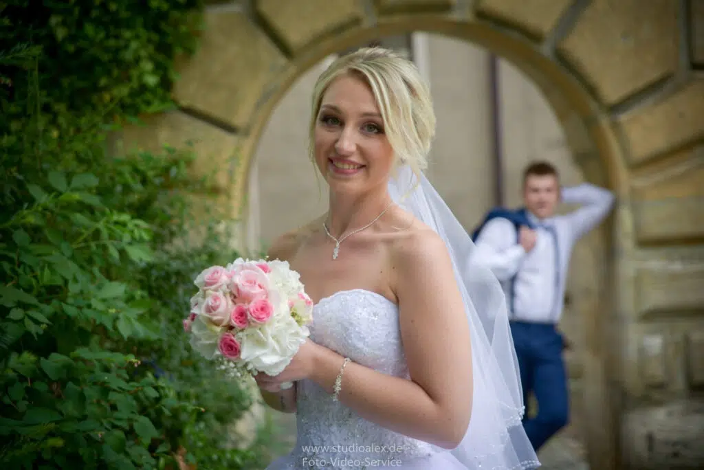 Braut mit Blumenstrauß im Vordergrund und der Bräutigam hinten - Hochzeitsfotografie Amberg