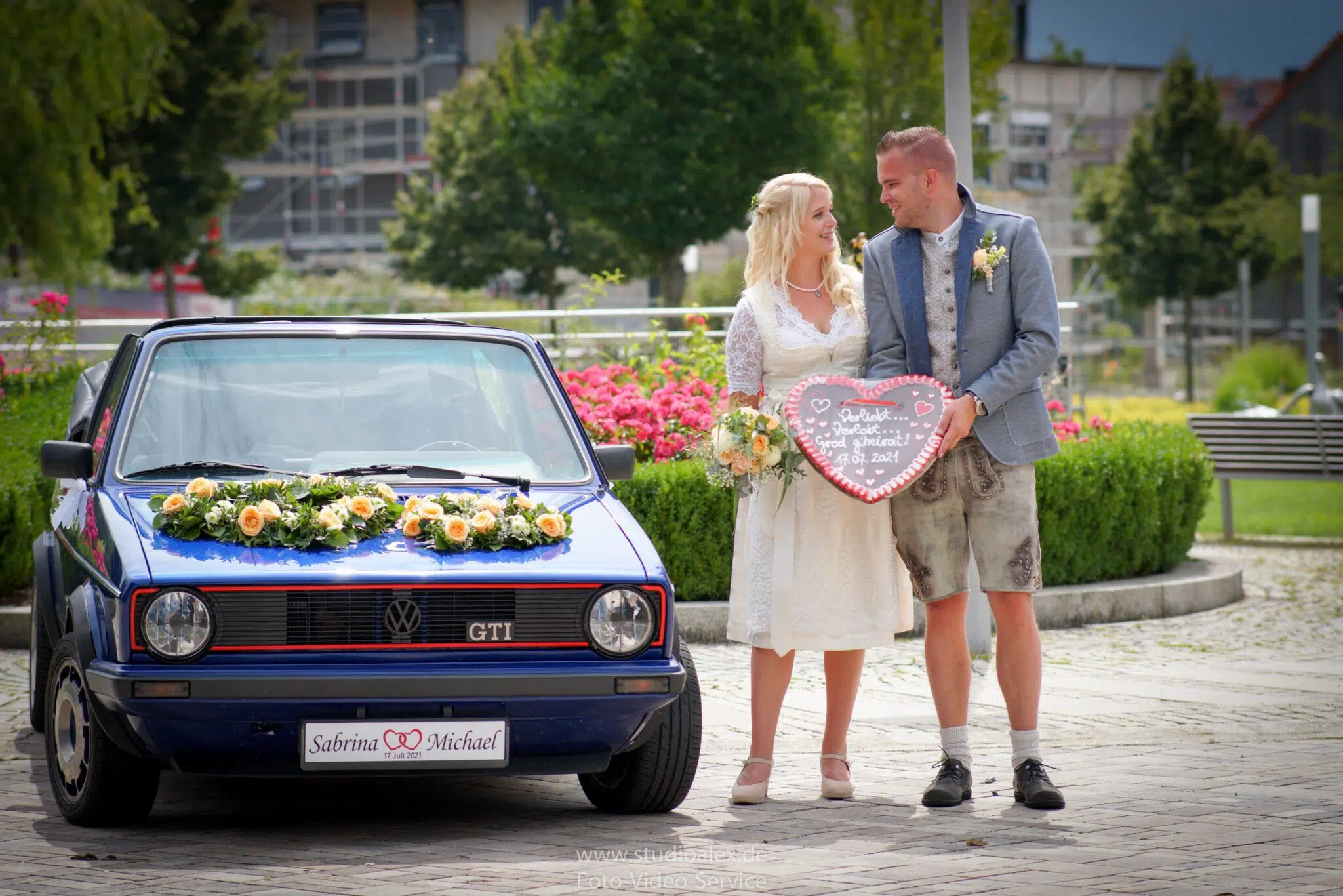 Brautpaar in Ursensollen bei Amberg vor ihrem Hochzeitsauto mit einem Herz in den Händen