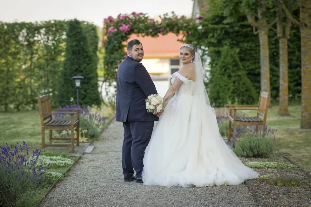 Braut und Bräutigam schauen zurück zu Alexander Dechant, welcher fotografiert